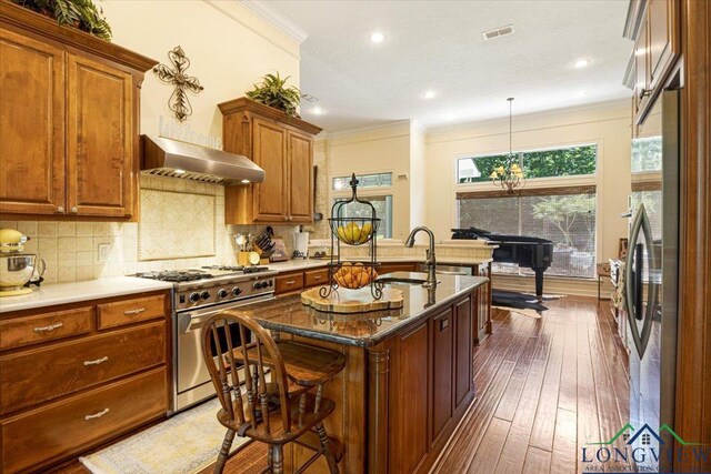 909 University Dr, Carthage, TX 75633 - kitchen featuring appliances with stainless steel finishes, a sink, dark wood-style floors, decorative backsplash, and crown molding