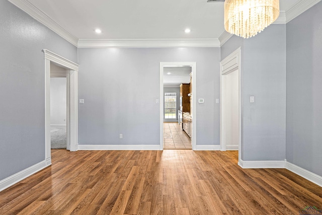 spare room with a chandelier, ornamental molding, and hardwood / wood-style floors