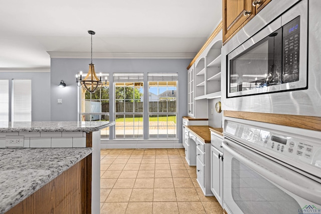 kitchen with stainless steel microwave, oven, light tile patterned flooring, white cabinets, and a chandelier