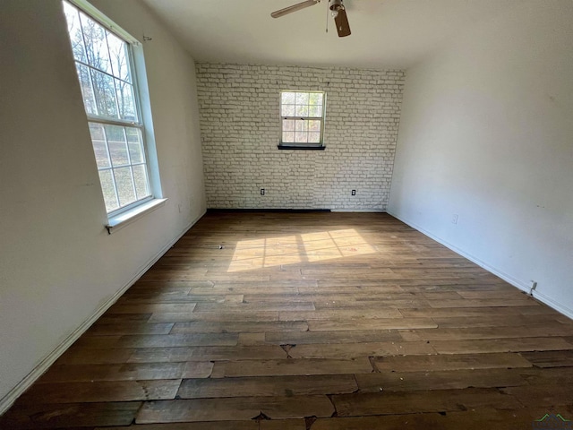 empty room featuring hardwood / wood-style flooring, a healthy amount of sunlight, and brick wall