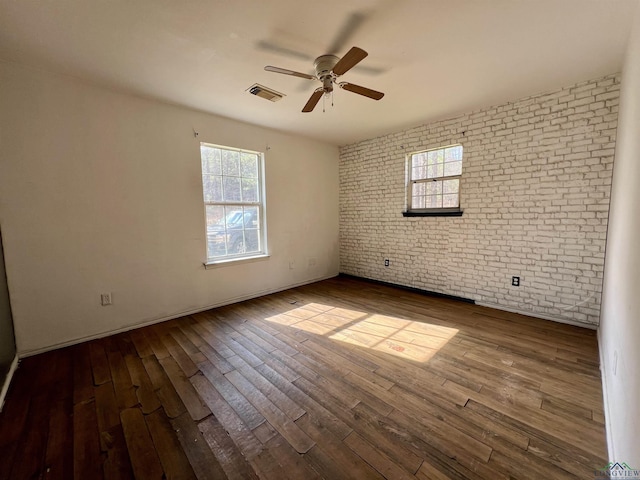 unfurnished room with wood-type flooring, ceiling fan, and brick wall