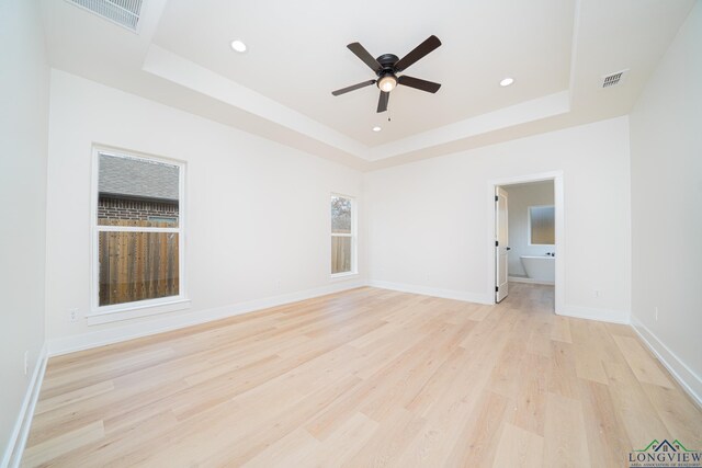 spare room featuring ceiling fan, a raised ceiling, and light wood-type flooring