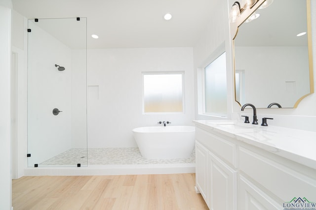 bathroom with plus walk in shower, vanity, and hardwood / wood-style flooring