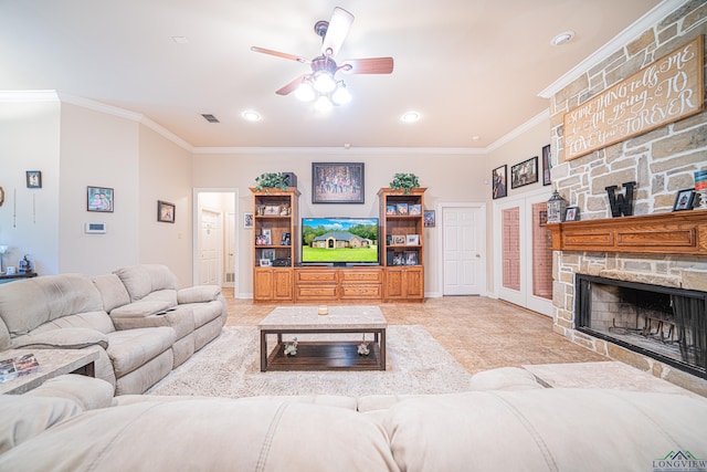 tiled living room featuring a stone fireplace, ceiling fan, and ornamental molding