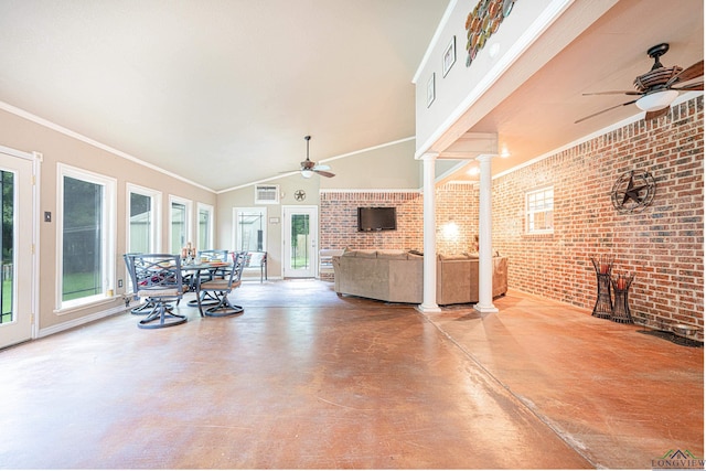 living room with ornate columns, brick wall, concrete flooring, vaulted ceiling, and crown molding