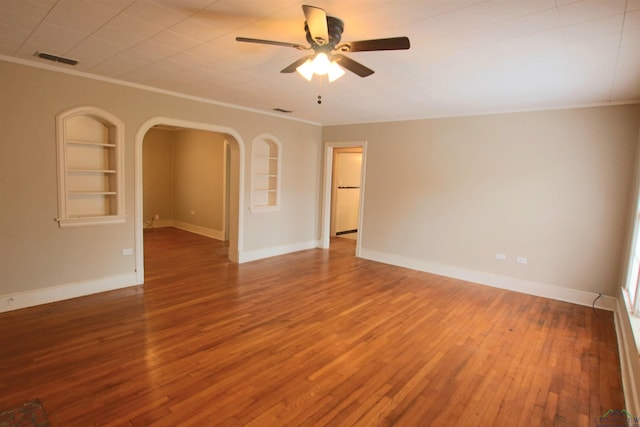 empty room with built in shelves, ornamental molding, ceiling fan, and hardwood / wood-style flooring