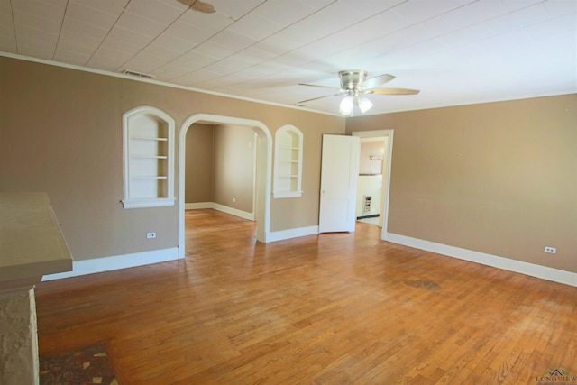 empty room featuring wood-type flooring, ceiling fan, and built in shelves