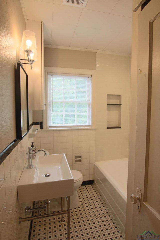 bathroom featuring ornamental molding, toilet, sink, and tile walls