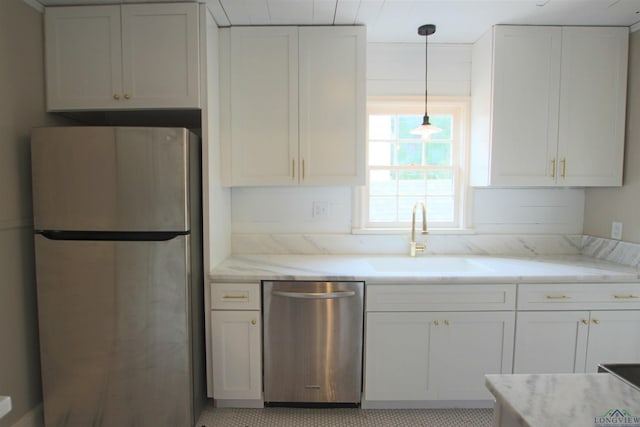 kitchen with sink, hanging light fixtures, stainless steel appliances, light stone countertops, and white cabinets