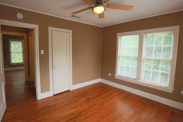 spare room with wood-type flooring, ornamental molding, and a wealth of natural light