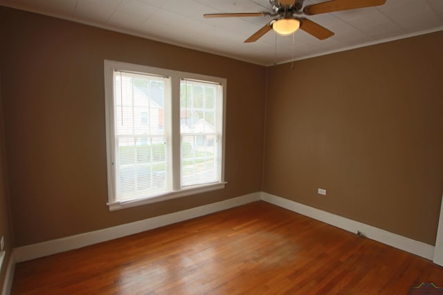 empty room with wood-type flooring, ornamental molding, and ceiling fan