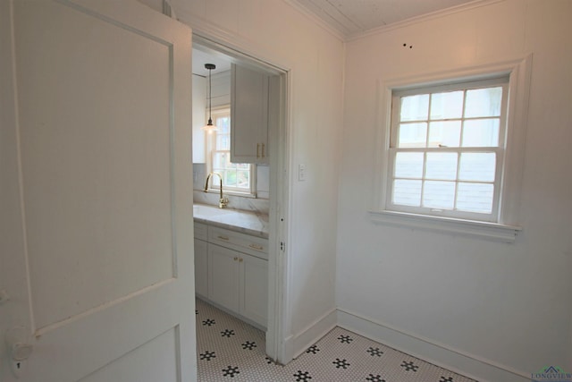 doorway to outside featuring ornamental molding, sink, and light tile patterned floors