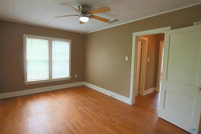 empty room featuring hardwood / wood-style floors, ornamental molding, and ceiling fan