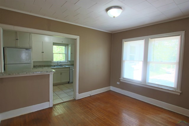 kitchen featuring sink, white refrigerator, ornamental molding, dishwasher, and light hardwood / wood-style floors