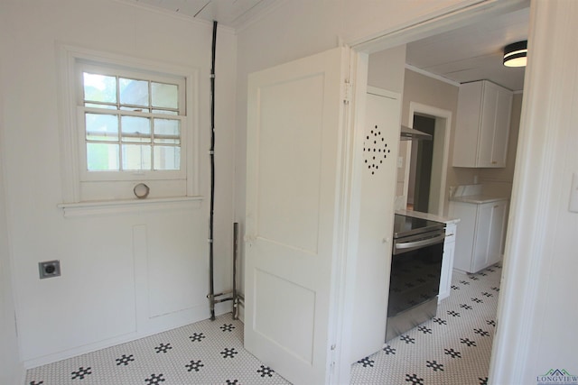 kitchen with ornamental molding, stove, and white cabinets