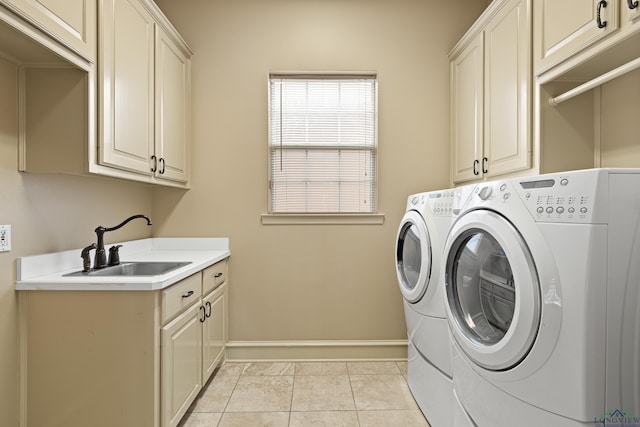 laundry room with cabinet space, light tile patterned floors, baseboards, separate washer and dryer, and a sink