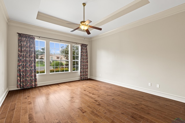 unfurnished room featuring hardwood / wood-style flooring, a ceiling fan, baseboards, ornamental molding, and a tray ceiling