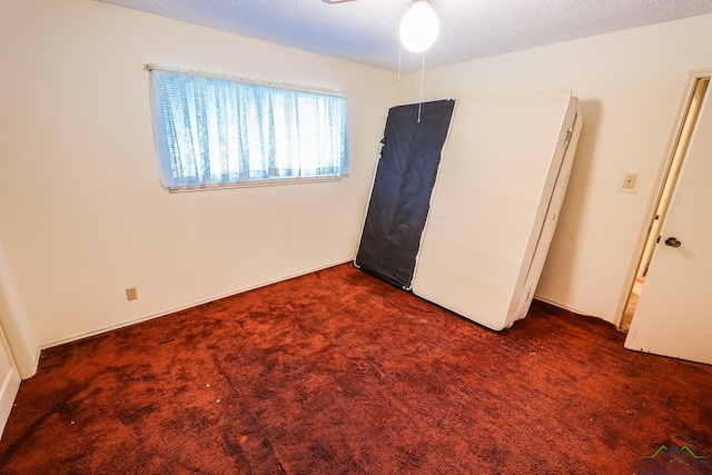 unfurnished bedroom featuring dark carpet and a textured ceiling