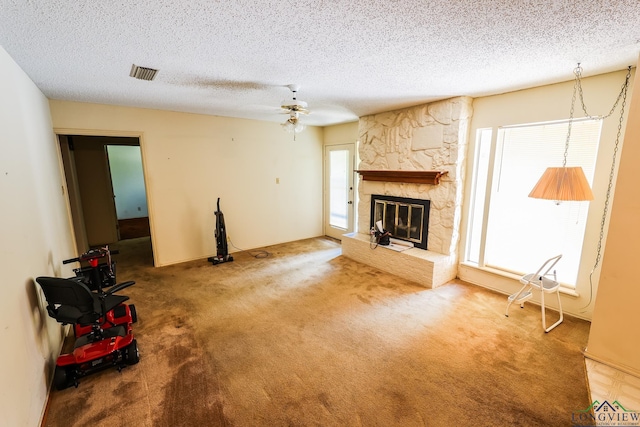 unfurnished living room featuring a textured ceiling, ceiling fan, plenty of natural light, and a fireplace