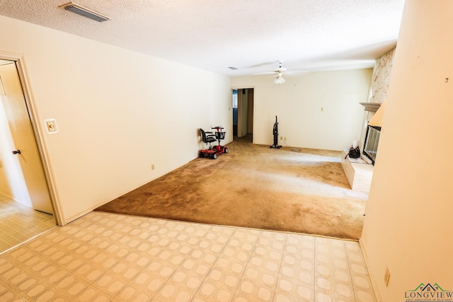 basement featuring ceiling fan, a fireplace, light colored carpet, and a textured ceiling