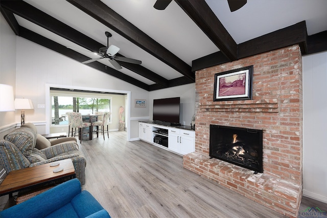 living room with lofted ceiling with beams, ceiling fan, a fireplace, and light hardwood / wood-style floors