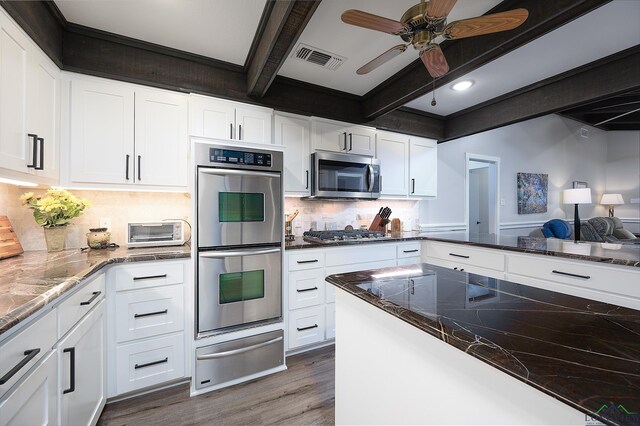 kitchen featuring appliances with stainless steel finishes, dark hardwood / wood-style flooring, tasteful backsplash, beam ceiling, and white cabinetry