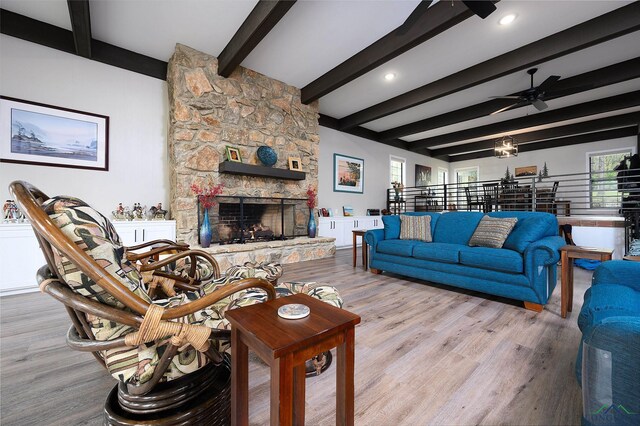 living room with beamed ceiling, ceiling fan, light hardwood / wood-style floors, and a fireplace