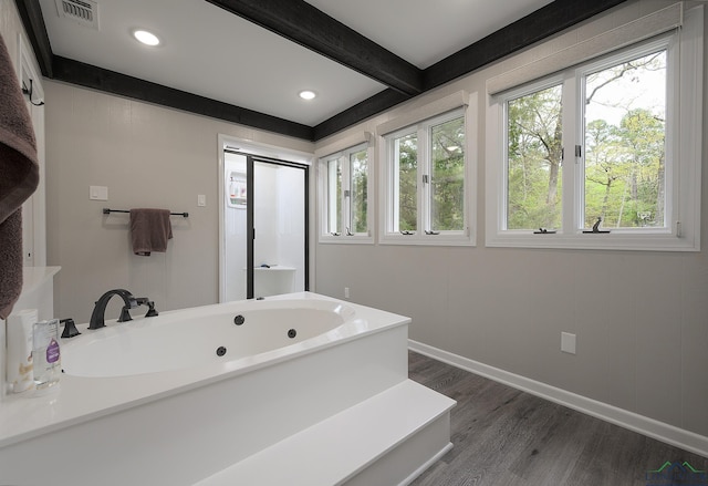 bathroom with a tub to relax in, beam ceiling, and hardwood / wood-style flooring