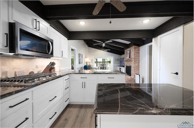 kitchen with tasteful backsplash, stainless steel appliances, wood-type flooring, vaulted ceiling with beams, and white cabinetry