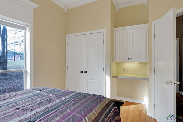 bedroom with ornamental molding, light hardwood / wood-style floors, and a closet