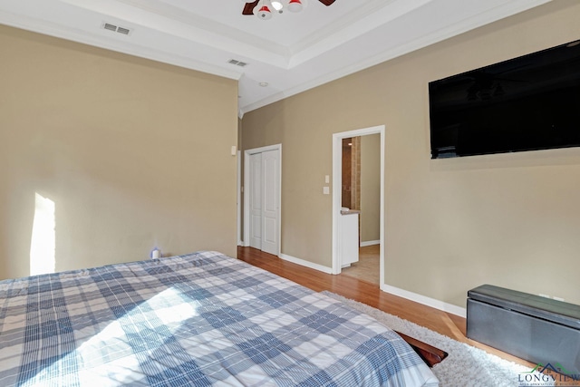 bedroom featuring a closet, ceiling fan, crown molding, a raised ceiling, and hardwood / wood-style flooring