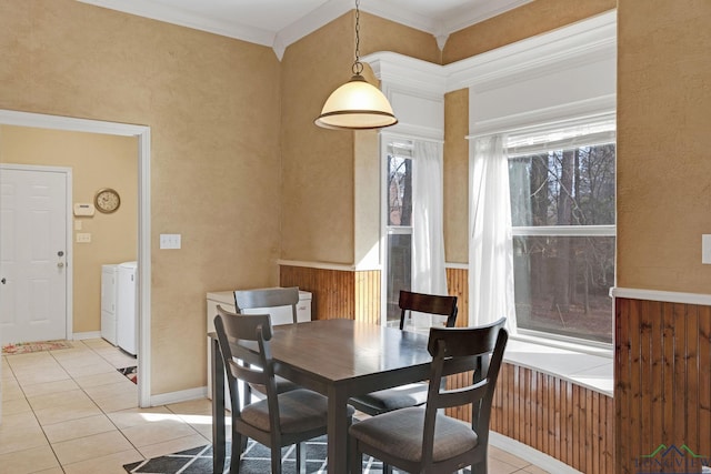 tiled dining area with ornamental molding and independent washer and dryer