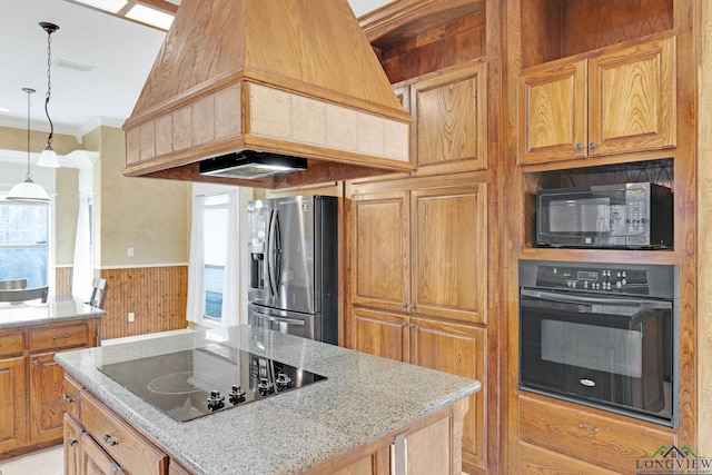 kitchen featuring premium range hood, light stone countertops, black appliances, decorative light fixtures, and crown molding