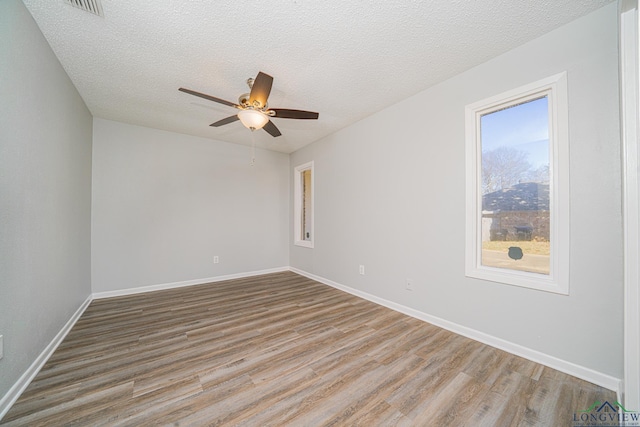 unfurnished room featuring ceiling fan, a healthy amount of sunlight, a textured ceiling, and light hardwood / wood-style flooring