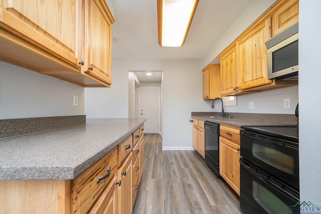 kitchen featuring light brown cabinetry, sink, black appliances, and light hardwood / wood-style flooring