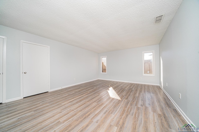 empty room featuring a textured ceiling and light hardwood / wood-style floors