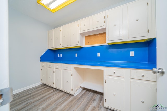 kitchen with light wood-type flooring, vaulted ceiling, and white cabinetry