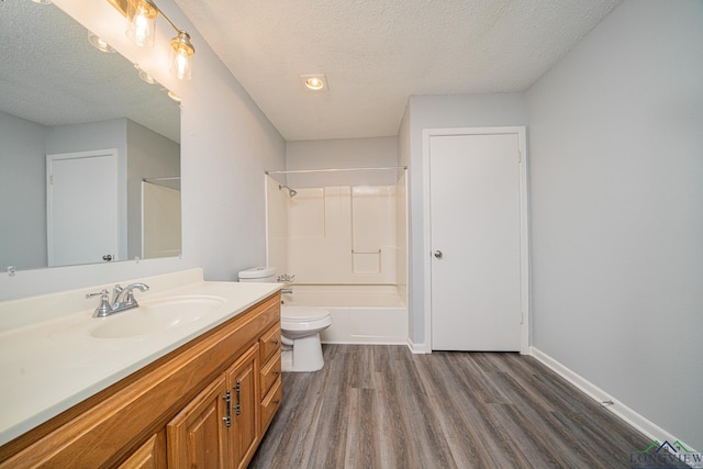 full bathroom featuring a textured ceiling, hardwood / wood-style floors, vanity, toilet, and shower / bathtub combination