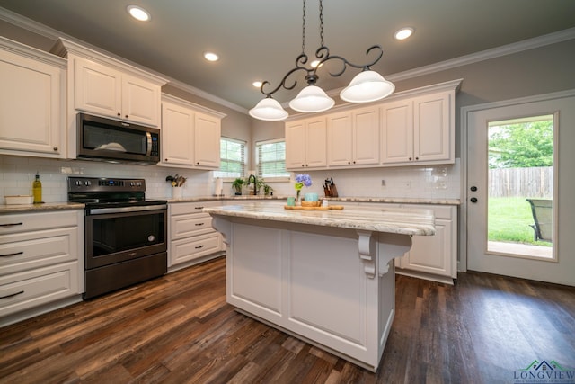 kitchen with hanging light fixtures, appliances with stainless steel finishes, a center island, and white cabinets