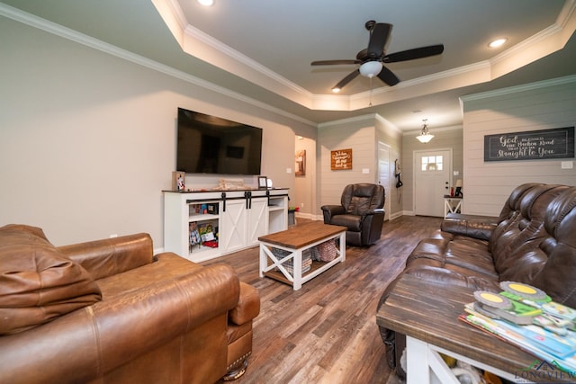 living room featuring ceiling fan, ornamental molding, a tray ceiling, and hardwood / wood-style floors