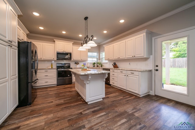 kitchen featuring appliances with stainless steel finishes, light stone countertops, white cabinets, a kitchen island, and decorative light fixtures