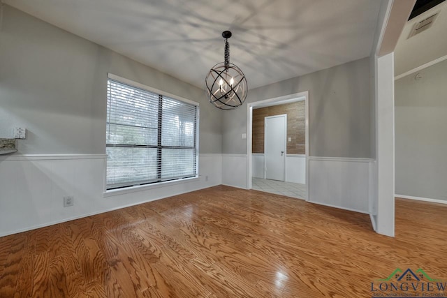 unfurnished dining area featuring light hardwood / wood-style flooring and a chandelier