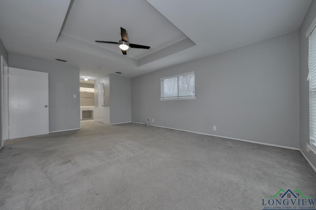 empty room with light carpet, ceiling fan, and a raised ceiling