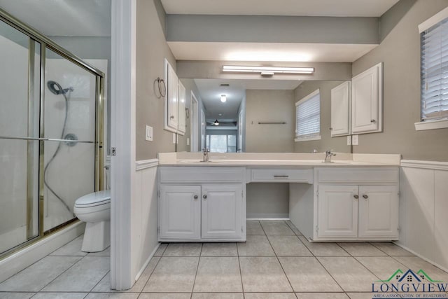 bathroom featuring toilet, tile patterned flooring, a shower with door, and vanity