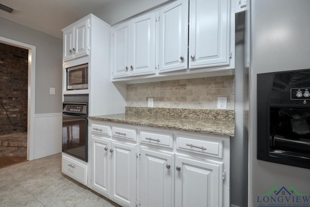 kitchen featuring white cabinets, backsplash, light stone countertops, and stainless steel appliances