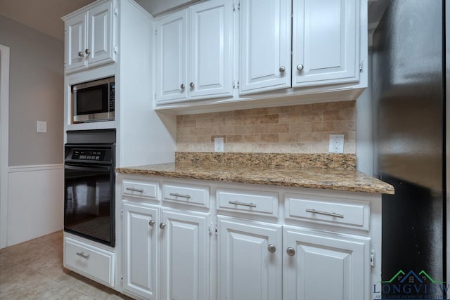 kitchen featuring light stone countertops, white cabinetry, backsplash, and black appliances