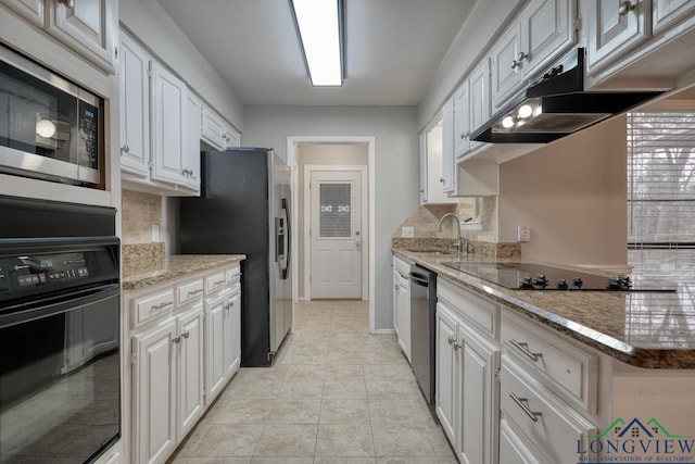 kitchen featuring tasteful backsplash, light stone countertops, black appliances, white cabinets, and sink