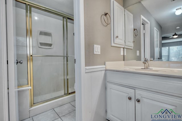 bathroom featuring ceiling fan, vanity, toilet, tile patterned floors, and a shower with door