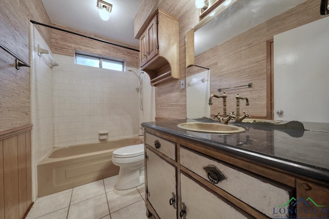 full bathroom with toilet, vanity, tile patterned flooring, tiled shower / bath, and wood walls