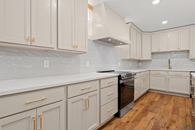 330 Forest Hls, Hallsville, TX 75650 - kitchen featuring custom range hood, stainless steel range with electric stovetop, light wood-style floors, light countertops, and decorative backsplash